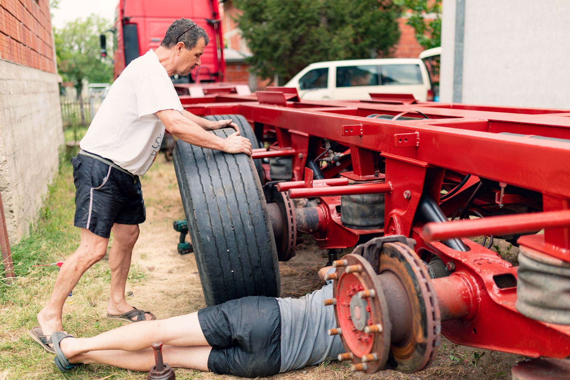 Men change a tire on a truck trailer.